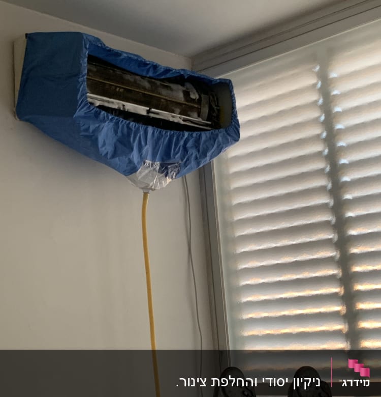 מזגן מכוסה בכיסוי כחול עם צינור ניקוז צהוב